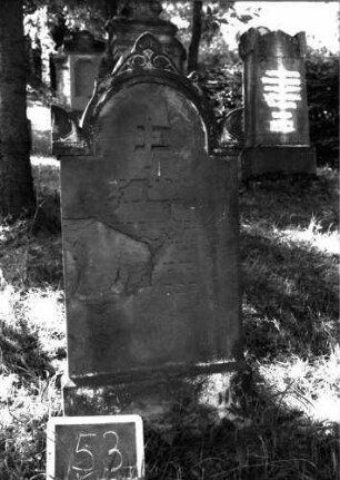 Grabstein 53 (Index: 100101011) Material: Sandstein Zustand: stark abgeblättert mit Textverlust Maße HxBxT: 127x49x9 cm Beschreibung: Stele, Sockel, eingezogener Rundbogenabschluß mit Akroteren: Grabstein 53