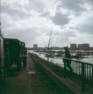 Sturmflut Hamburg 1962. Überflutetes Gelände in der Nähe eines Neubaugebietes. Vordergrund: Bundeswehrsoldaten kommen im LKW zur Hilfe