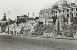 Blick über Gebäudereste und gestapelte Steine gegen Ruine der Reformierten Kirche und Neues Rathaus