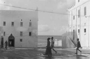 Indische Häuser in Mogadischu : Blick über eine Straße auf zwei Häuser indischen Stils. Zwischen den Häusern ist der Indische Ozean zu ekennen.