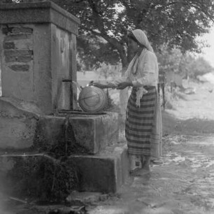 Roma-Mädchen mit Wasserflasche am Brunnen in Karlowo im Rosental