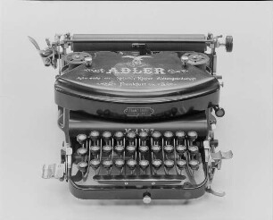 Stoßstangenschreibmaschine "Adler" (Modell 7). Vorderanschlag (sofort sichtbare Schrift), 30 Tasten, doppelte Umschaltung, Farbband. Vorderansicht von oben : Stoßstangenschreibmaschine "Adler" (Modell 7). Vorderanschlag (sofort sichtbare Schrift), 30 Tasten, doppelte Umschaltung, Farbband. Vorderansicht von oben. Baujahr: 1899 oder 1900; Hersteller: Adlerwerke vormals Heinrich Kleyer AG Frankfurt (Main); Verwalter: Sächsische Landesbibliothek - Staats- und Universitätsbibliothek Dresden (SLUB), Stenografische Sammlung, Inventar-Nummer R i 0001