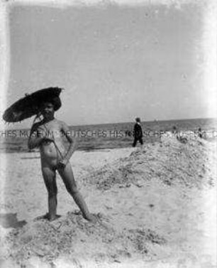 Kind mit Sonnenschirm am Strand