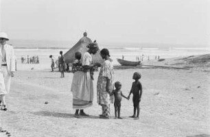 Reisefotos Senegal. Einheimische am Strand. Im Vordergrund junge Frau mit Kindern