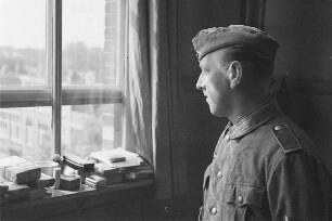 Zweiter Weltkrieg. Niederlande unter deutscher Besatzung. Deutscher Wehrmachtsangehöriger am Fenster eines Dienstzimmers (wohl bei Den Haag)
