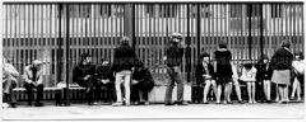 Jugendliche, die auf Bänken sitzen, einige stehen davor (Altersgruppe 14-17)