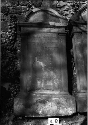Grabstein 48 (Index: 99629549) Material: Sandstein Zustand: abgeblätt/verwitt/Textverlust Maße HxBxT: 185x77x18 cm Beschreibung: Stele mit aufgesetztem Rundbogenabschluß Symbolik: zwei vierblättrige Blüten: Grabstein 48