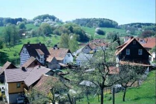 Ortsansicht von Norden aus; rote Dächer und strukturreiche Landschaft