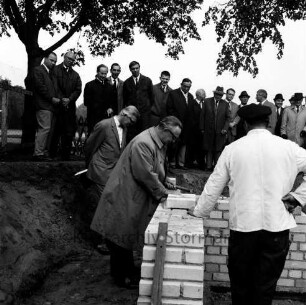 Stormarnhalle: Grundsteinlegung: Bürgerworthalter Georg Koch mauert den letzten Grundstein ein, dahinter Gäste