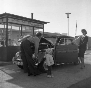 Schwab-Markt. Außenansicht, davor Personenkraftwagen mit geöffneter Motorhaube und Personen
