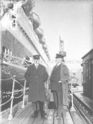 Zwei Männer in Mänteln, mit Marinemützen, vor dem Hochseepassagierdampfer "Bremen", Bremerhaven