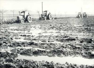 Feldarbeit : Land- und Viehwirtschaft - Bodenbearbeitung und -pflege. Traktoren auf feuchten Feldern