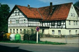 großes, winkliges Fachwerkgebäude, davor Containerstellplatz