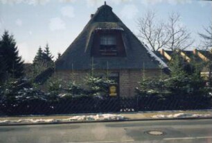 Alte Landstraße 18: giebelständige Fachwerkkate mit Reetdach: Straßenfront mit Eingangstür und großer Gaube [umgebaut]