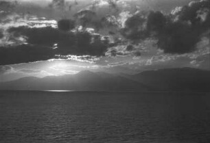 Messina gegen Sonne und Ätna : Blick vom Schiff auf das Meer und die bergige Küstenlandschaft von Messina