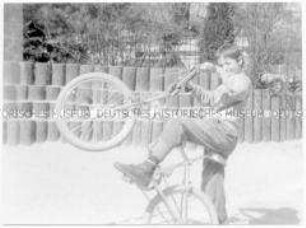 Junge mit Fahrrad auf einem Spielplatz (Altersgruppe bis 14)