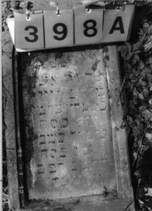 Grabstein 398 (Index: 99792066) Material: Sandstein Zustand: verwittert und abgeblättert mit Textverlust, Stele liegend Maße HxBxT: 75x37x15 cm Beschreibung: Stele, Rundbogenabschluß, rechteckig erhöht, Schriftfeld eingetieft Symbolik: Blüte: Grabstein 398A