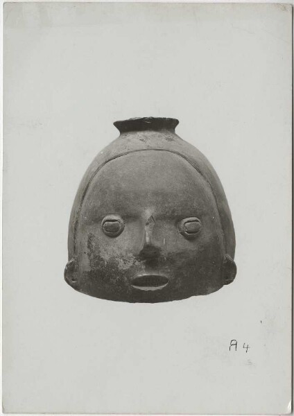 Water jug with plump human face. Traces of bolus. Height: 19 cm.