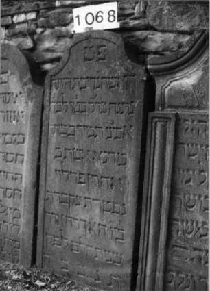 Grabstein 1068 (Index: 99630571) Material: Sandstein Zustand: leicht verwittert Maße HxBxT: 113x50x10 cm Beschreibung: Stele mit eingezogenem Segmentbogenabschluß, Schriftfeld eingetieft: Grabstein 1068