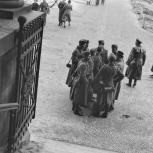 Wehrmachtssoldaten im Mantel stehen vor einer Treppe, Soldaten auf Urlaub