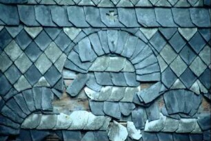 beschädigte Schieferornamente an einer Hauswand