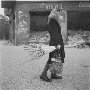 Berlin. Junge Frau transportiert Holzstücke in einem Tragebeutel