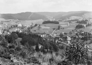 Nové Hamry : Blick vom westlichen Hang des Rohlautals über Nové Hamry mit dem Bahnhof in der Bildmitte, der Kirche am linken Bildrand und dem oberen Ortsteil im Hintergrund.
