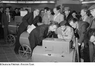 Besucher der Leipziger Herbstmesse 1954 betrachten elektrische Geräte