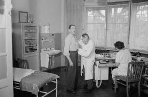 Patient, Arzt und eine Frau während einer medizinischen Untersuchung