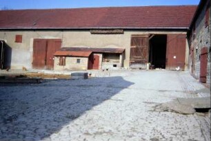 Blick in einen großen Hof; Kalksteinpflasterung, hinten Scheune