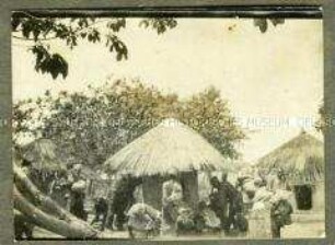 Afrikanische Träger und Askari in einer Hüttensiedlung