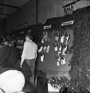 Kreisjägerschaft Stormarn e.V.: Rohlfshagen/Kupfermühle: Gastwirtschaft "Kupfermühle": Saal: Mitgliederversammlung: Ausstellungstafel mit Auswahl an Jagdtrophäen aus den Hegeringen: vorn links Personen