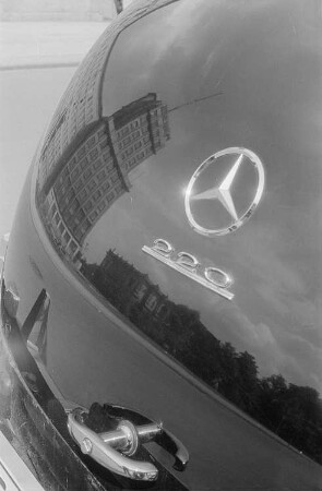 Im Heck eines Mercedes spiegelt sich ein Hochhaus