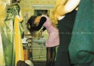 Mädchen kämmt sich vor einem Waschbecken kopfüber die Haare (Altersgruppe 14-17)