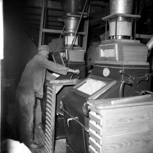 Müller in einer Mühle beim Bedienen eines Walzenstuhles