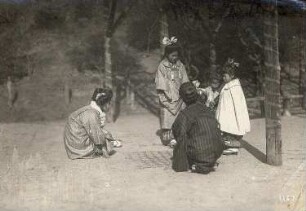 Nara, Japan. Spielende Kinder. Drei Japanerinnen und Kinder spielen mit gezeichneten Kästchen im Sand