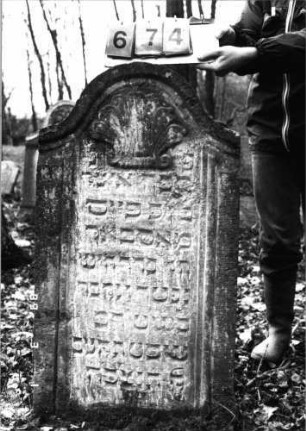 Grabstein 674 (Index: 99752411) Material: Sandstein Zustand: leicht verwittert Maße HxBxT: 113x60x10 cm Beschreibung: Stele, Konvexbogenabschluß, Schriftfeld eingetieft Symbolik: Muschel: Grabstein 674