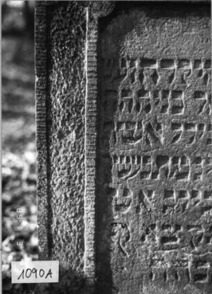 Grabstein 1090 (Index: 99753295) Material: Sandstein Zustand: leicht beschäd/verwitt/Textverlust Maße HxBxT: 104x69x10 cm Beschreibung: Stele, eingezog, Rundbogenabschluß, rechteck. Schriftfeld eingetieft Symbolik: Menora: Grabstein 1090A