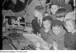 Kinder an einem Stand mit Holzspielzeug auf dem Weihnachtsmarkt