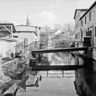 Trave: Stadtarm: in der Mitte Brücke: rechts und links Gebäude: im Hintergrund links Turm der Peter-Paul-Kirche