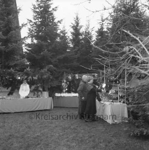 Rethwischdorf: Grundstück des stellvertretenden Kreispräsidenten Ernst Eick: Weihnachtsmarkt: vorn Marktstände mit Besuchern: dahinter Tannenreihe: im Hintergrund links Turm der Christuskirche