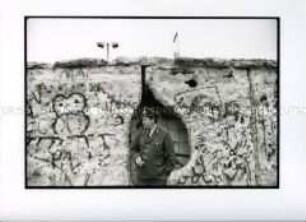 Grenzer an der durchlöcherten Berliner Mauer