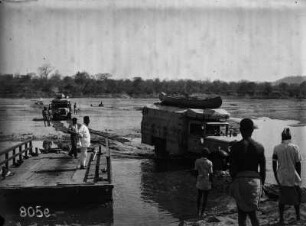 Autos in Landschaft : Expeditionsteilnehmer und Automobile in einer Landschaft mit einem Gewässer