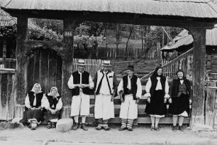 Männer und Frauen in Trachten vor einem Hoftor (im Kreis Maramures ?)