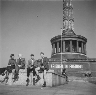 Berlin-Tiergarten. Großer Stern. Paar und zwei junge Männer am Fuß der Siegessäule (mit der Aufschrift "Frieden in Freiheit")