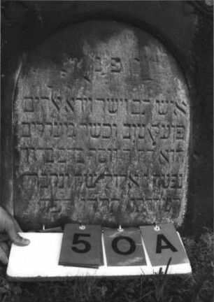 Grabstein 50 (Index: 100113798) Material: Sandstein Zustand: mittelstark verwittert Maße HxBxT: 74x58x13 cm Beschreibung: Stele mit eingezogenem Spitzgiebel, vertiefter Textteil in Form einer Stele mit Rundbogen: Grabstein 50A