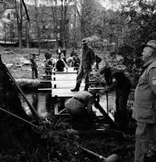 Sühlen: Trave: Wanderweg zwischen Sühlen und Bebensee (Kreis Segeberg): Fußgängerbrücke: Bau: Technisches Hilfswerk (THW) Bad Segeberg: Verlegung der Holzbohlen auf Trägern durch freiwillige Helfer: hinten zwischen Bäumen "Zettlersche Mühle" [ehemalige Kupfermühle] mit Nudelfabrik