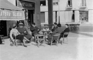 Straßencafé : Blick auf eine Gruppe von Personen, die vor einem Straßencafé sitzen