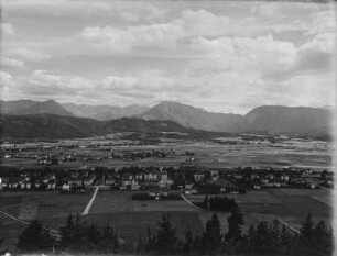 Stadtbild : Eine Stadt umgeben von Feldern, im Hintergrund Berge
