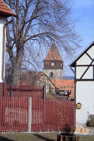Blick über ein Lattentor zum Kirchturm